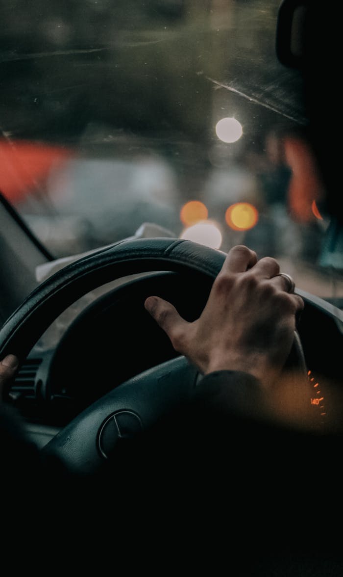 Close-up of a hand holding a steering wheel, capturing the essence of night driving.