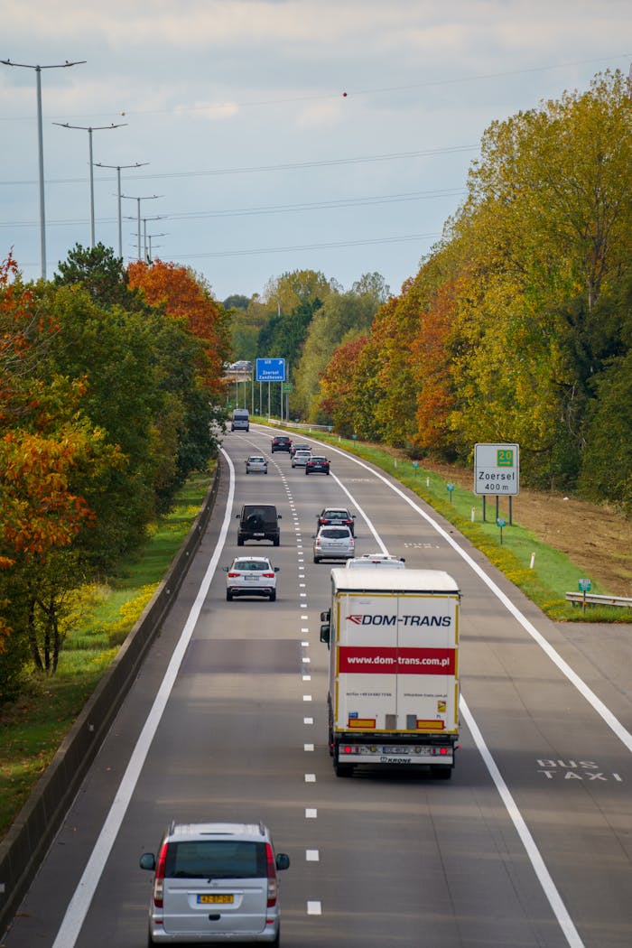 Highway traffic during autumn season with colorful foliage along the roadside, showcasing vibrant fall colors.